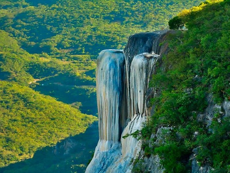 The petrified falls at Hierve el Agua, white mineral running down a green cliff