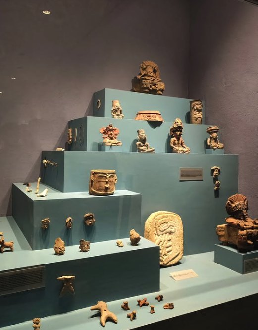 Zapotec ceramic urns and carved figures on display in the Monte Alban site museum